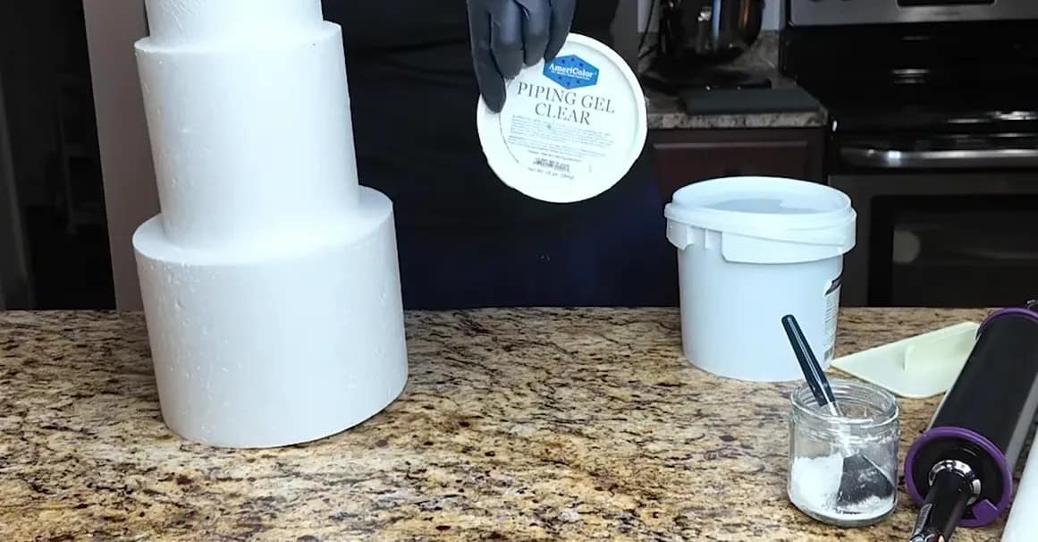 Piping gel clear and fondant supplies on a countertop near the dummy cake