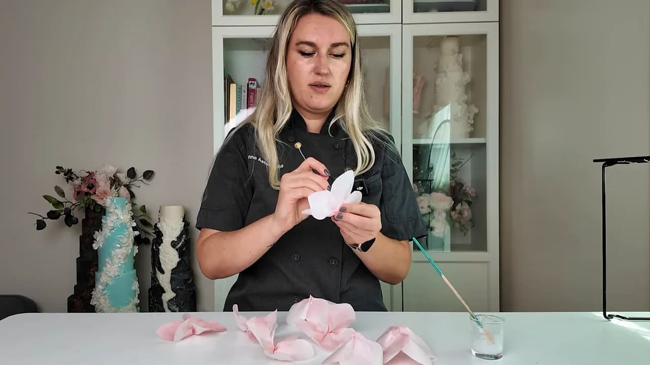Chef holding a completed wafer paper flower with petals and center for wedding cake decoration