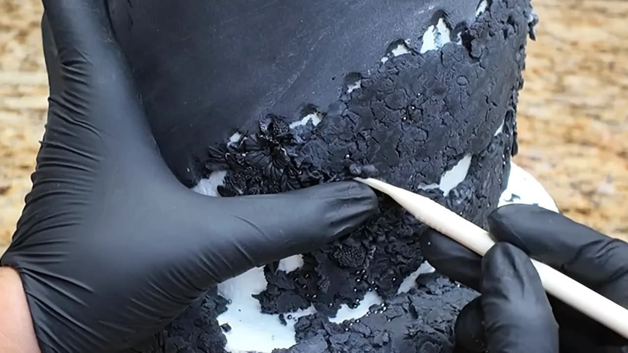 Dresden tool blending the edges of bas-relief into rough black fondant texture on a wedding cake dummy