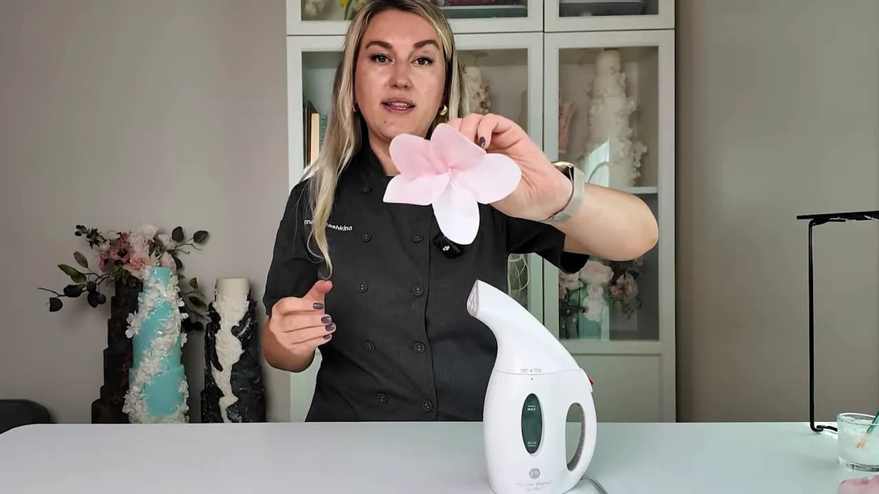 Finished pink wafer paper flower bloom held up during wedding cake wafer paper flower tutorial