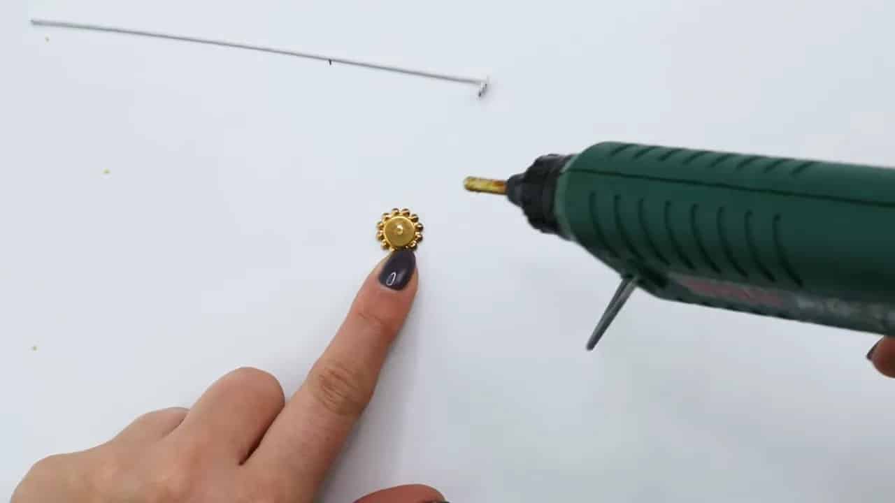 Hot glue gun applying glue to a wafer paper flower center before inserting the wire