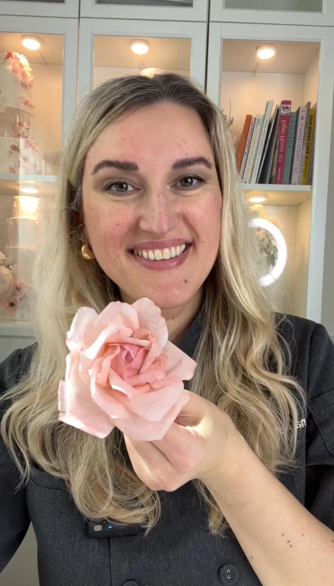 Chef Anna holding a handmade pink wafer paper rose in her studio
